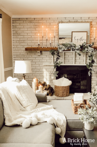 This cozy winter decor in her living room is so inviting! I love the way she styles the fireplace mantel decor. #cozywinterdecor
