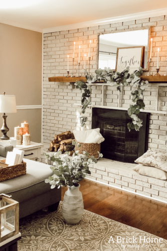 This cozy winter decor in her living room is so inviting! I love the way she styles the fireplace mantel decor. #cozywinterdecor