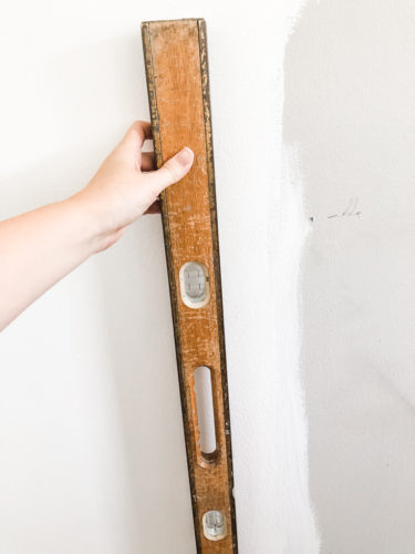 Learn how to paint an arch on a wall in any room for a budget-friendly statement! See how she made a DIY compass to make this large arch look symmetrical. #archonawall