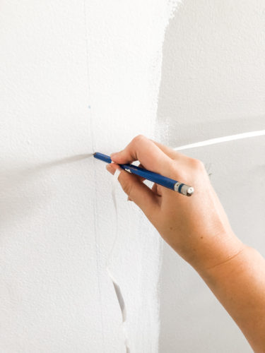 Learn how to paint an arch on a wall in any room for a budget-friendly statement! See how she made a DIY compass to make this large arch look symmetrical. #archonawall