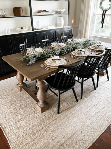 Neutral and rustic Christmas table decor using greenery, antlers and jute chargers #rusticchristmastabledecor #rusticchristmastablescape #rusticchristmasdecor