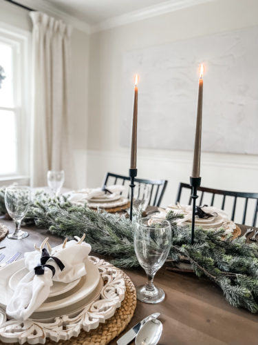 Neutral and rustic Christmas table decor using greenery, antlers and jute chargers #rusticchristmastabledecor #rusticchristmastablescape #rusticchristmasdecor