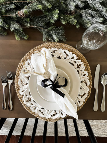 Neutral and rustic Christmas table decor using greenery, antlers and jute chargers #rusticchristmastabledecor #rusticchristmastablescape #rusticchristmasdecor