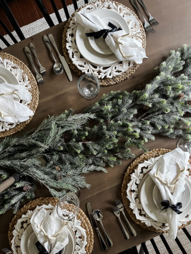 Neutral and rustic Christmas table decor using greenery, antlers and jute chargers #rusticchristmastabledecor #rusticchristmastablescape #rusticchristmasdecor