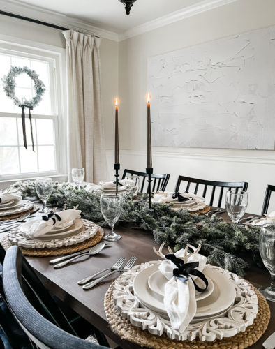 Neutral and rustic Christmas table decor using greenery, antlers and jute chargers #rusticchristmastabledecor #rusticchristmastablescape #rusticchristmasdecor