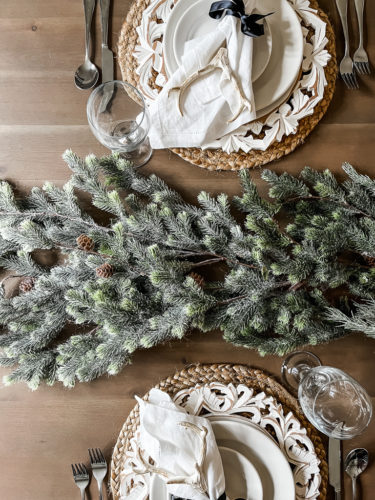 Neutral and rustic Christmas table decor using greenery, antlers and jute chargers #rusticchristmastabledecor #rusticchristmastablescape #rusticchristmasdecor